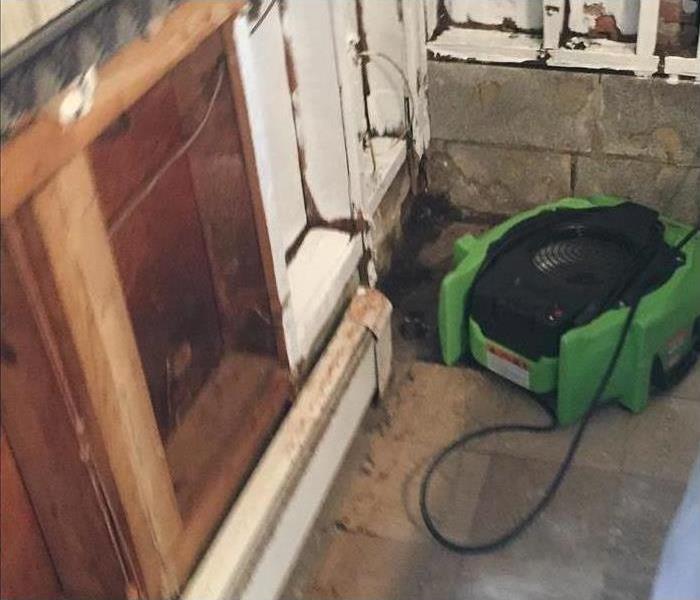 Air mover placed by a cabinet drying affected area in a home